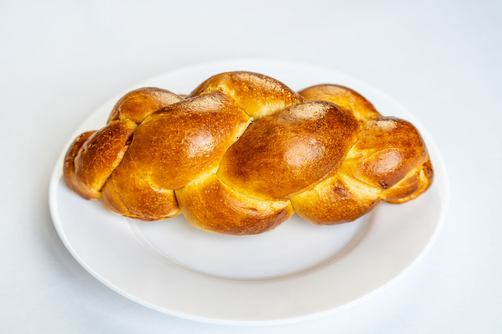 Upieczona chałka na białym talerzu.