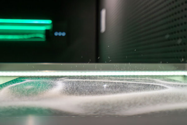 Ulotne ślady cząstek w komorze mgłowej podświetlone jasnym światłem.