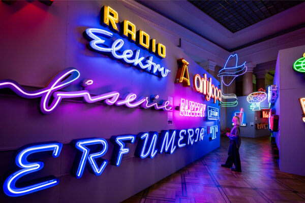 Muzeum Neonów, kobieta ogląda kolorowe neony zawieszone na ścianach.
